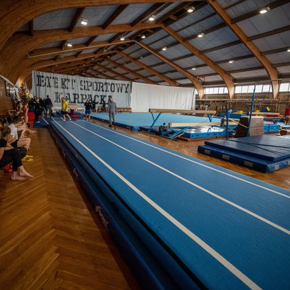 Wnętrze sali sportowej, na pierwszym planie rozbieg zwieńczony kozłem gimnastycznym.